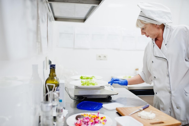 Köchin bereitet Salat in der Küche des italienischen Restaurants zu.