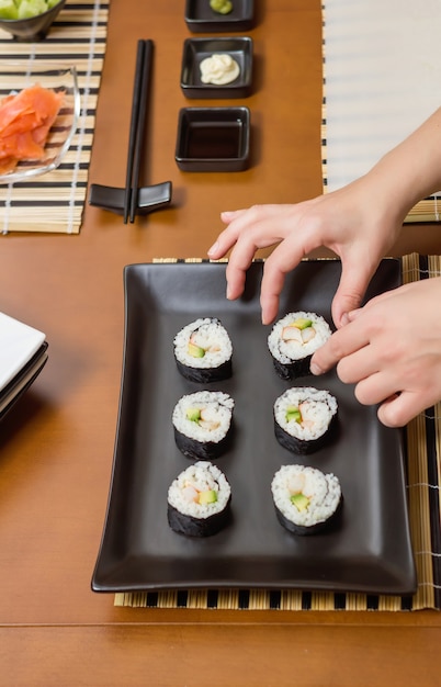 Köchin legt japanische Sushi-Rollen auf ein Tablett