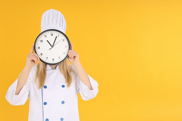 Köchin mit Uhr auf gelbem Hintergrund