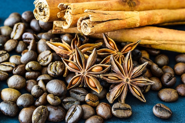 Körner von Kaffee, Anis und Zimtstangen auf einem dunkelblauen Hintergrund