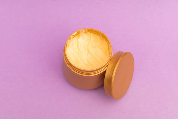 Körperbutter im goldenen Glas mit violettem Hintergrund eine Werbeaufnahme des Produkts