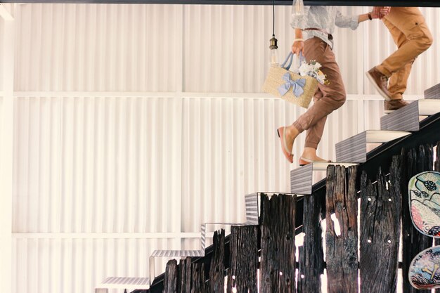 Körperteile eines jungen Paares, das Händchen durch die Treppe hält