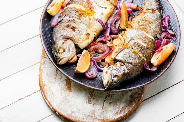 Köstliche Bachforelle gebraten in Zwiebeln und Zitrone. Gebackene Regenbogenforelle, Meeresfrüchte