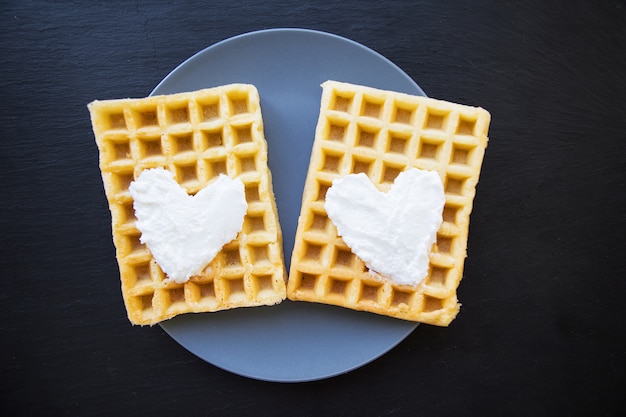 Köstliche belgische Waffeln mit Sahne auf einem schwarzen Hintergrund