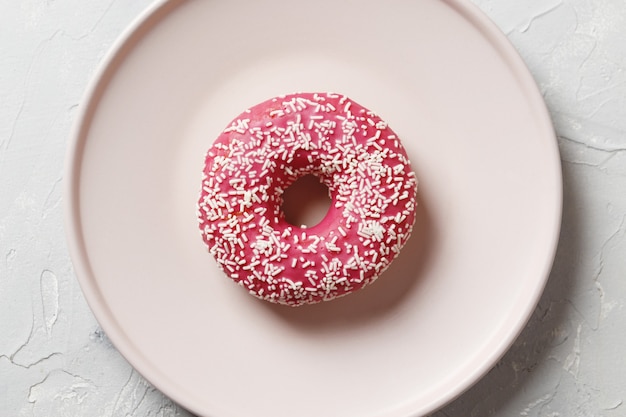 Köstliche bunte Donuts mit Streuseln auf stilvollem Teller auf weißem Tisch mit Konfetti, flach. Party-Konzept. Keine Diät. Schokoriegel bei der Hochzeitsfeier. Lila und rosa Donuts