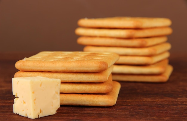 Köstliche Cracker mit Käse auf Holztisch auf braunem Hintergrund