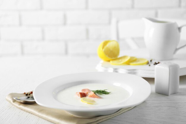 Köstliche Cremesuppe mit Fisch und Zitronenscheiben auf weißem Tisch im Restaurant