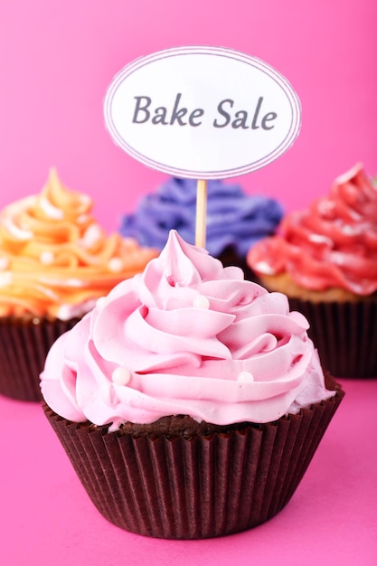 Köstliche Cupcakes mit Inschrift auf farbigem Hintergrund