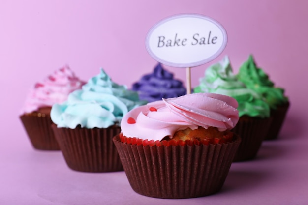 Köstliche Cupcakes mit Inschrift auf farbigem Hintergrund