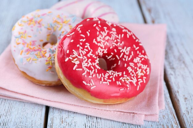 Köstliche Donuts mit Zuckerguss auf Serviette auf Holzhintergrund