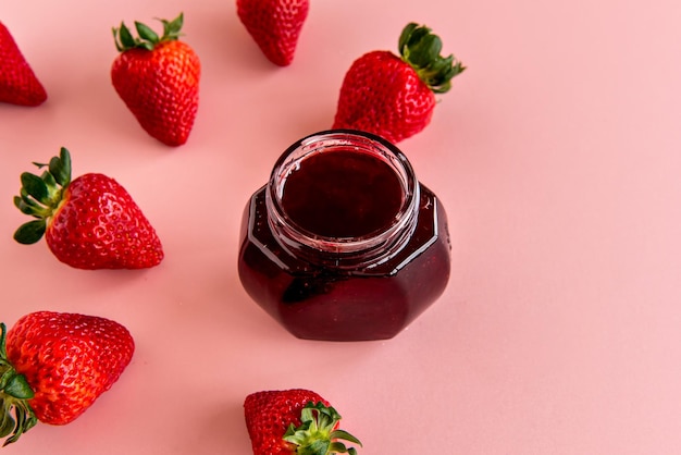 Köstliche Erdbeermarmelade auf einem rosa Hintergrund mit Erdbeeren