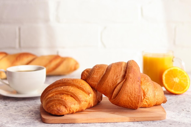 Köstliche französische Bäckerei Croissants mit Orangensaft, Orangenfrucht und Kaffee auf dem Tisch Frühstück