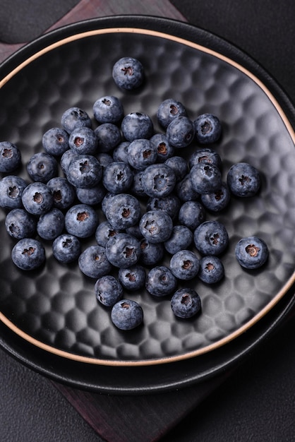 Köstliche frische Heidelbeeren auf einem strukturierten schwarzen Betonhintergrund