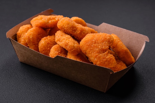 Köstliche, frische, knusprige Hühnernuggets auf dunklem Betonhintergrund