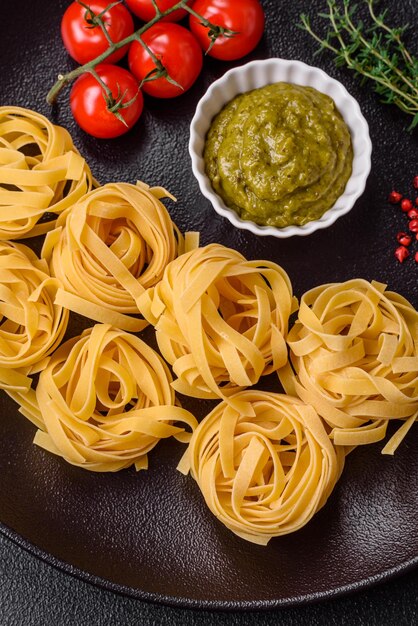 Foto köstliche frische pasta bestehend aus pesto-sauce mit salz, gewürzen und kräutern auf dunklem betongrund