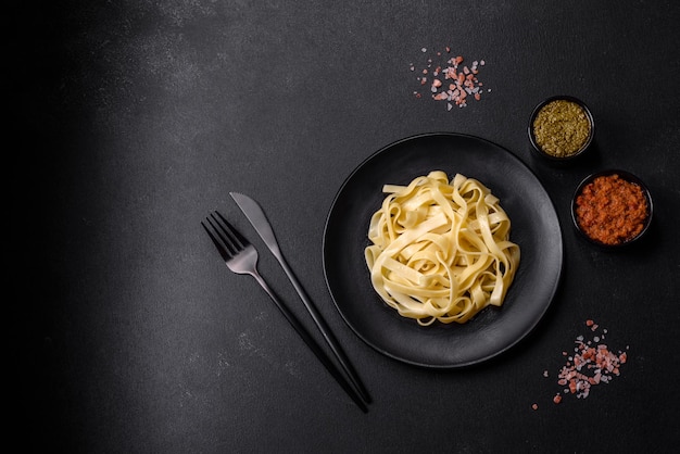 Köstliche frische Pasta mit Pesto-Sauce und Meeresfrüchten auf einem schwarzen Teller