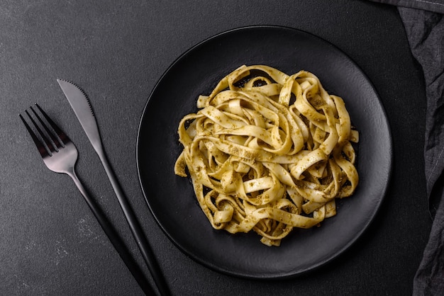 Köstliche frische Pasta mit Pesto-Sauce und Meeresfrüchten auf einem schwarzen Teller