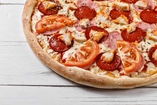 Köstliche frische Pizza mit Hühnerschinken-Tomate serviert auf Holztisch