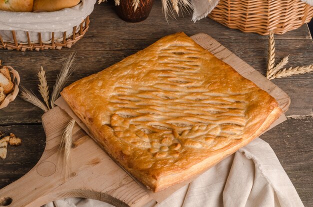 Köstliche frische quadratische Torte gefüllt mit lockigen Teigdekorationen auf hölzernem Hintergrund