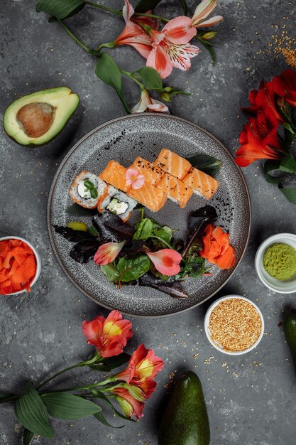 Köstliche frische Sushirollen mit Lachs und Philadelphia-Käse auf grauer Platte auf dunklem Steinhintergrund