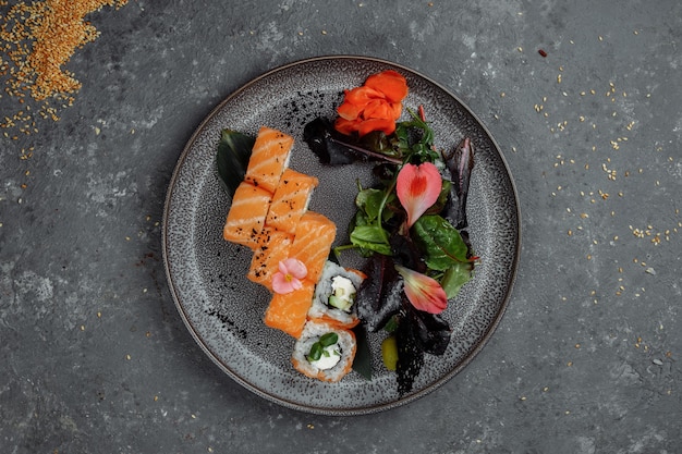 Köstliche frische Sushirollen mit Lachs und Philadelphia-Käse auf grauer Platte auf dunklem Steinhintergrund