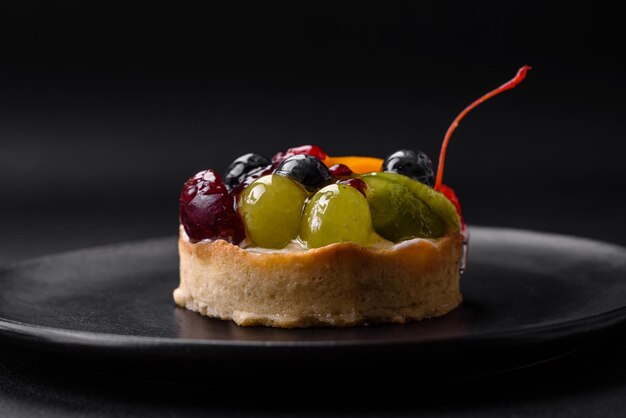 Köstliche frische Torte mit Blaubeerkirschentrauben auf einer schwarzen Keramikplatte