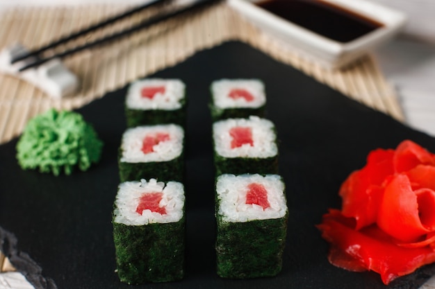 Köstliche, frische und leckere Sushi-Rollen mit Thunfisch serviert auf schwarzem Schiefer, Nahaufnahme. Japanische Meeresfrüchte, Maki.