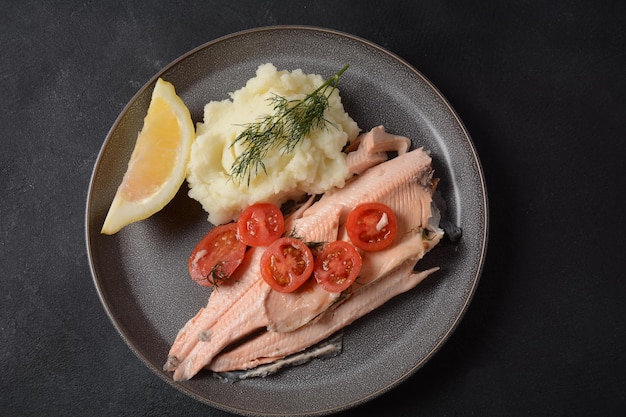 Foto köstliche gebackene forelle mit kirschtomaten-olivenöl-zitronensaft und frischem dill auf weißer platte mit zitronenscheiben