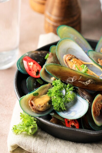 Köstliche gedämpfte Muscheln im asiatischen Stil mit rotem Pfeffer, grüner Zwiebel, Kurkuma und Knoblauch aus nächster Nähe