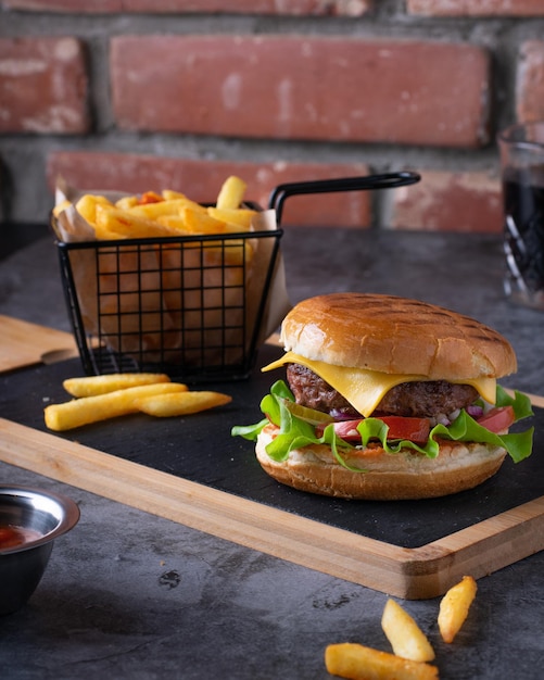 Köstliche gegrillte hausgemachte Burger mit Pommes Frites und Ketchup auf dunklem Hintergrund vertikal