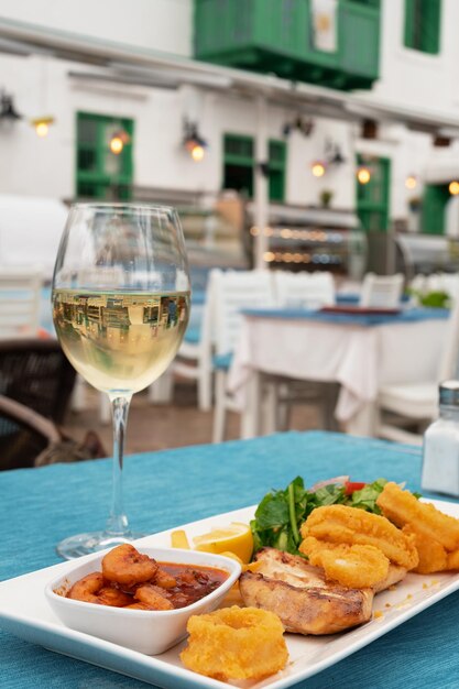 Köstliche gegrillte Meeresfrüchte auf Tellergericht und Glas Weißwein im Restaurant im Freien vertikales Foto