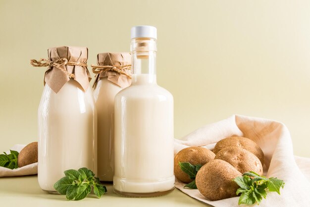 Köstliche, gesunde Kartoffelmilch in Glasflaschen auf beigem Pastellhintergrund, Nahwinkelquelle für Eisen-Vitamin C