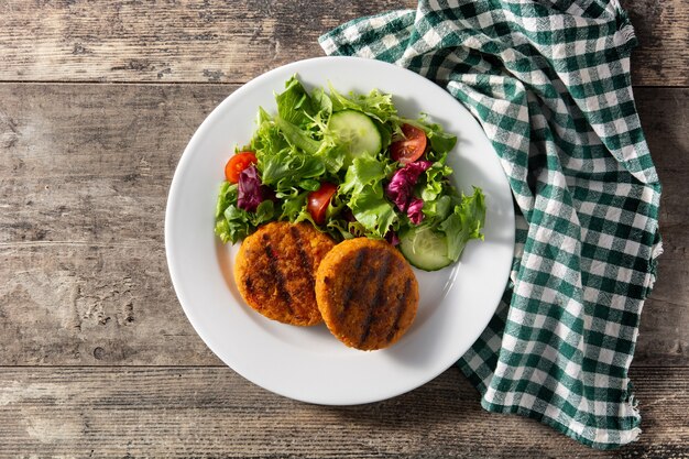 Köstliche gesunde Kichererbsenburger und Salat auf Holztisch