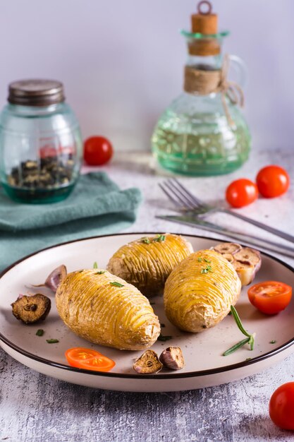 Köstliche hausgemachte gebackene Hasselback-Kartoffeln mit Knoblauch und Rosmarin auf einem Teller Vertikale Ansicht