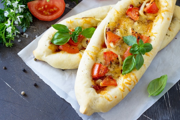 köstliche hausgemachte griechische Pizza mit Salami-Tomaten-Zwiebeln und Käse auf dunklem Steinhintergrund