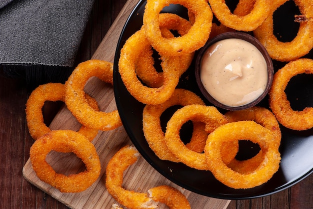 Foto köstliche hausgemachte knusprig gebratene zwiebelringe mit pikanter sauce