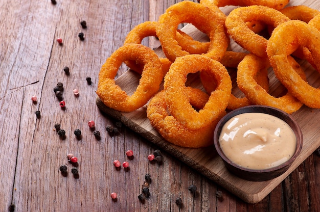 Köstliche hausgemachte knusprig gebratene Zwiebelringe mit scharfer Sauce. Platz kopieren