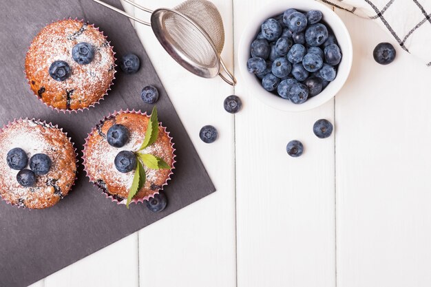 Köstliche hausgemachte Muffins mit Blaubeeren auf dem weißen Holztisch