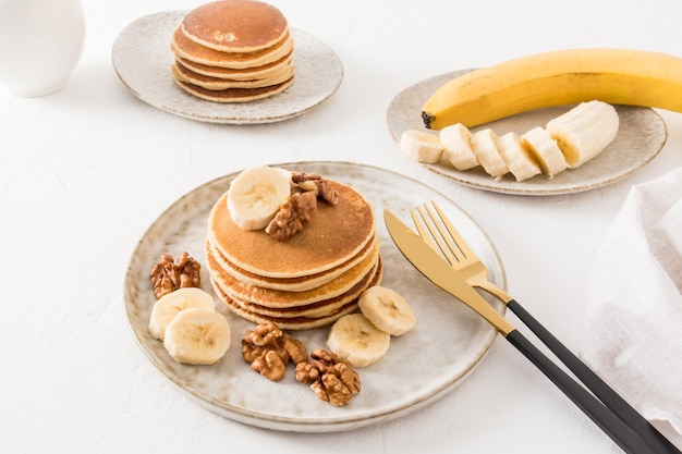 Köstliche hausgemachte Pfannkuchen auf einer Keramikplatte mit Bananenscheiben und Walnüssen ein traditionelles amerikanisches Dessert