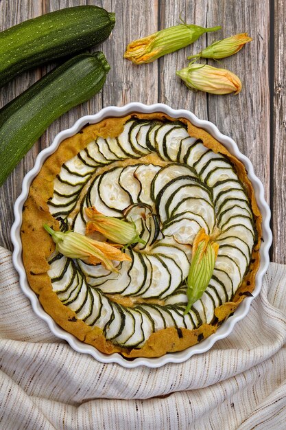 Köstliche hausgemachte Zucchini-Torte mit Quark und Kräutern, umgeben von Blumensamen und Zucchini