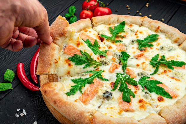 Köstliche heiße Pizza mit Lachsrucola und verschiedenen Gewürzen auf Holztisch, essfertig