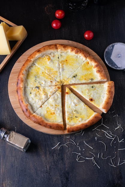 Köstliche italienische Pizza vier Käsesorten mit Basilikumtomaten und Olivenöl auf einem Holztisch flach gelegt