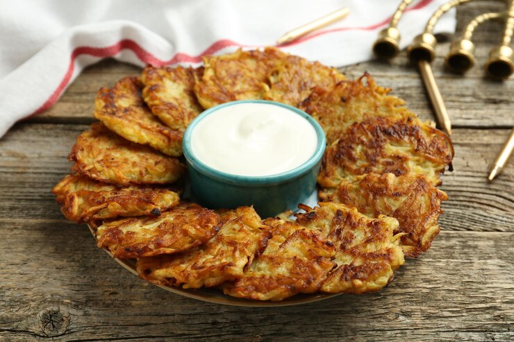 Foto köstliche kartoffel-pancakes mit sauerkreme menorah und kerzen auf einem holztisch nahaufnahme hanukkah festliche speisen