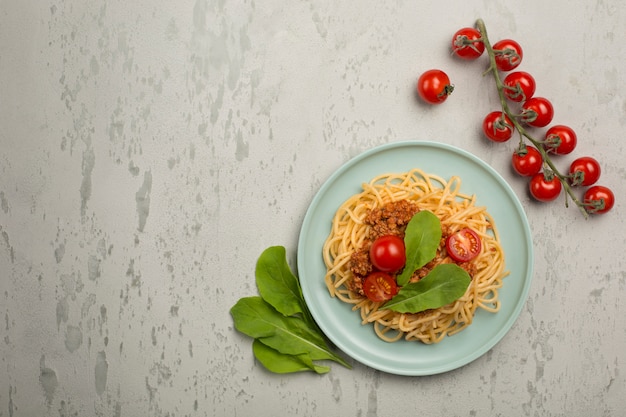 Köstliche klassische italienische Bolognese-Nudeln mit Tomaten auf einem Teller auf hellgrauem Hintergrund.