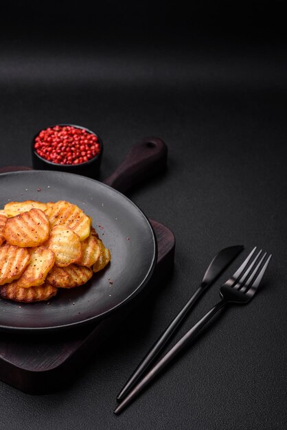 Köstliche knusprige Bratkartoffeln in Scheiben auf einer schwarzen Keramikplatte