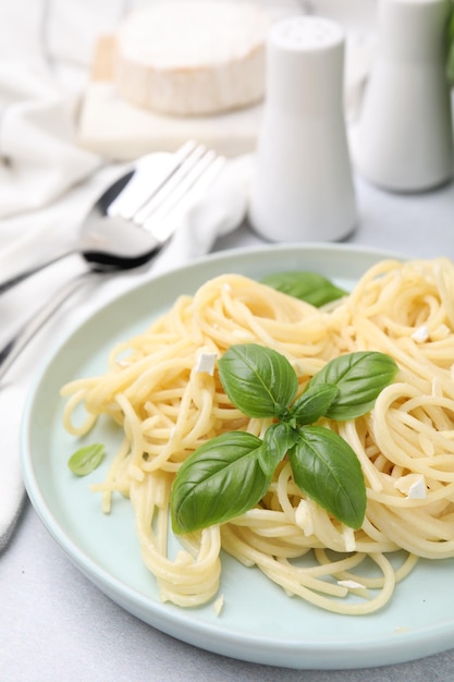 Köstliche Pasta mit Brie-Käse und Basilikumblättern auf hellgrauem Tisch, Nahaufnahme, Platz für Text