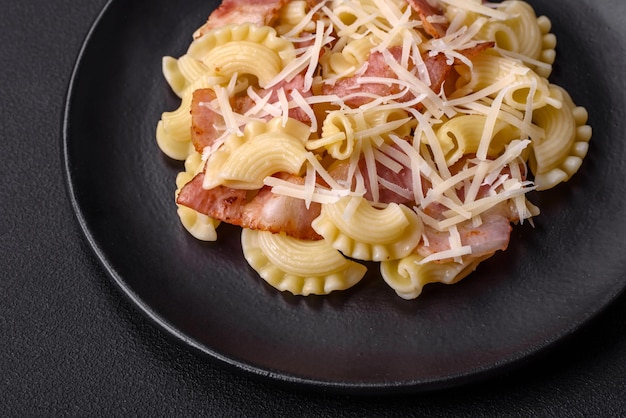 Köstliche Pasta mit Speck und Parmesankäse auf einer schwarzen Keramikplatte