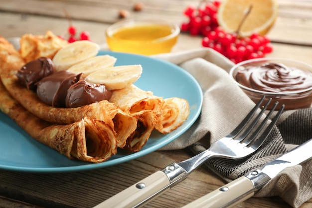 Köstliche Pfannkuchen mit Schokolade und Banane auf blauem Teller