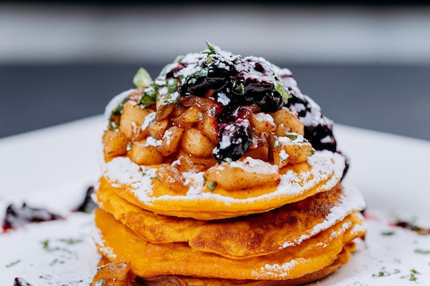 Köstliche Pfannkuchen werden mit Johannisbeermarmelade und Äpfeln auf einem essfertigen Teller serviert