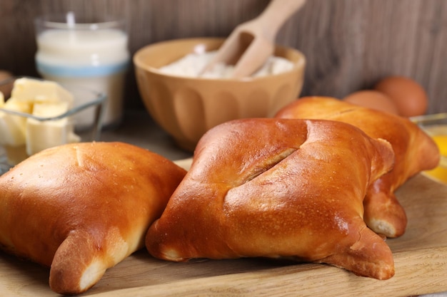 Köstliche Pirozhki-Gefüllte Gebäckkuchen und Zutaten auf einem Holztisch in Nahaufnahme